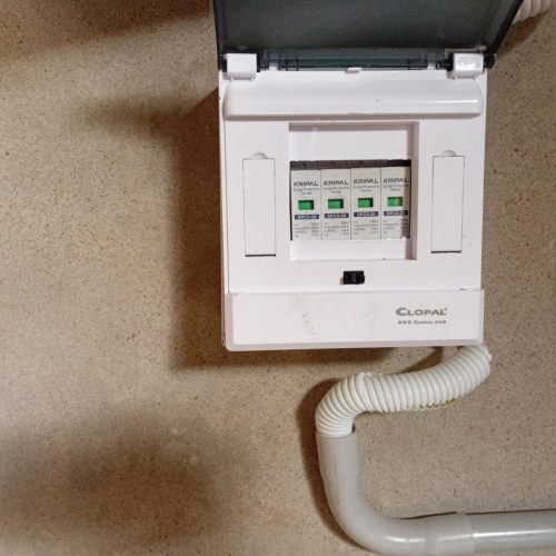 A white electrical box with a hose connected to it, positioned against a neutral background.