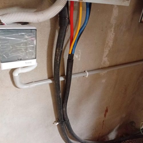 Wall-mounted electrical box filled with various wires and cables.